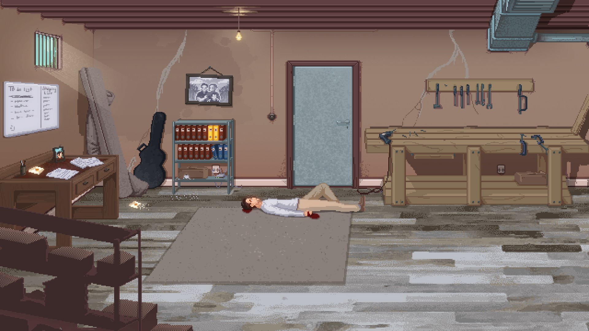 ryan lies on the floor of a basement with a bloody hand. around him is a workbench, desk, shelves, and a guitar case